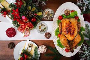 al forno tacchino o pollo. il Natale tavolo è servito con un' tacchino, decorato con luminosa orpello e candele. fritte pollo, tavolo. Natale cena. piatto posizione. superiore Visualizza foto