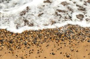 l'onda dell'oceano lambisce la sabbia e la spiaggia di ciottoli