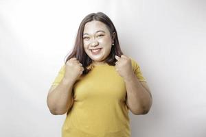 un' giovane asiatico grande dimensione donna con un' contento riuscito espressione indossare un' giallo camicia isolato di un' bianca sfondo foto