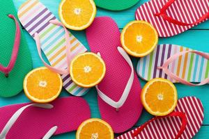 estate divertimento tempo e Flip flop. pantofole e arancia frutta su blu di legno sfondo. finto su e pittoresco. superiore Visualizza. sandali foto