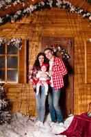 mamma e papà posa con loro affascinante poco figlia nel decorato Natale studio. nuovo anno foto sessione.