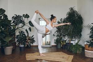 attraente giovane donna guardare concentrato mentre praticante yoga a casa foto