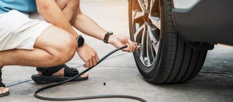 uomo guidatore che gonfia a mano i pneumatici del veicolo, rimuovendo il tappo di azoto della valvola del pneumatico per controllare la pressione dell'aria e riempire l'aria sulla ruota dell'auto alla stazione di servizio. self service, manutenzione e sicurezza foto