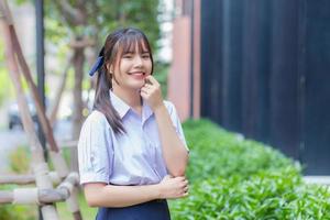 bellissimo asiatico alto scuola alunno ragazza nel il scuola uniforme con con fiducia mentre lei sembra a il telecamera. foto