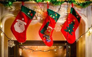 tre calze natalizie appese al caminetto decorato foto