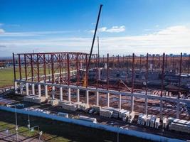 costruzione gru sollevamento il travi di il metallo telaio di il edificio su un' calcestruzzo base. foto