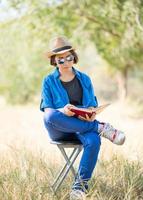 donna indossare cappello e lettura il libro su sedia foto