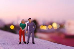 miniatura coppia persone figura in piedi a tetto vedendo tramonto Visualizza di il città, san valentino giorno concetto foto