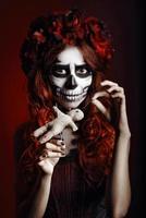 giovane donna con il trucco muertos (teschio di zucchero) piercing bambola voodoo foto