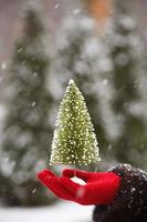 albero di natale in mano a sfondo di neve