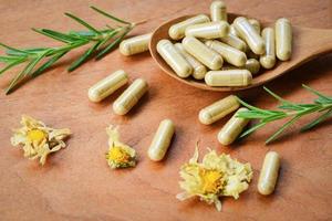 erbaceo medicina estratto a partire dal natura non tossico droga biologico Prodotto su di legno cucchiaio e selvaggio fiore rosmarino - erbaceo capsule a partire dal erbe aromatiche salutare stile di vita foto