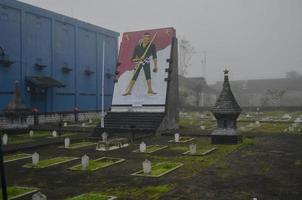 malang, Indonesia - ottobre 22 2022 il presto nebbia coperto il cortile di il dell'eroe grave, il lapide nel il primo piano sagomato il statua di il eroe. il atmosfera è inquietante. Halloween foto