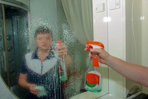 un' donna pulisce un' specchio con un' tovagliolo a partire dal sporco e placca a partire dal acqua a casa foto