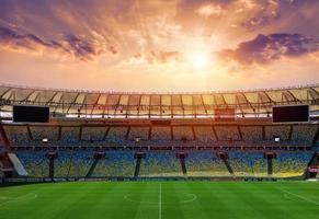 calcio campo nel il gli sport stadio. prato illuminato nel il centro di il circostante luci . foto