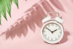 bianca allarme orologio e le foglie ombre su pastello rosa sfondo foto