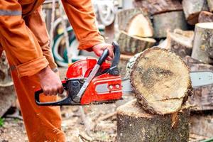 uomo con motosega taglio il albero. lavoratore nel protettivo Ingranaggio. foto