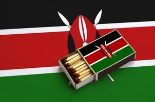 Kenia bandiera è mostrato nel un Aperto scatola di fiammiferi, quale è pieno con fiammiferi e bugie su un' grande bandiera foto