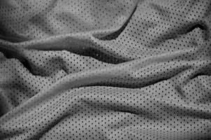 grigio sport capi di abbigliamento tessuto struttura sfondo. superiore Visualizza di grigio stoffa tessile superficie. buio pallacanestro camicia. foto