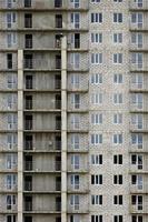 strutturato modello di un' russo pietra bianca Residenziale Casa edificio parete con molti finestre e balcone sotto costruzione foto