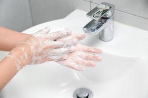 donna uso sapone e lavaggio mani sotto il acqua rubinetto. foto