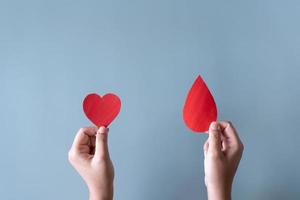 sangue donazione o chirurgia concetto. umano Tenere sangue cartello e un' rosso cuore forma. foto