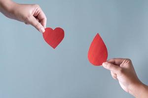 sangue donazione o chirurgia concetto. umano Tenere sangue cartello e un' rosso cuore forma. foto