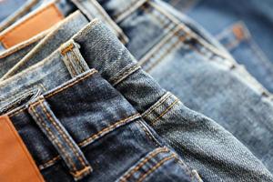 molti jeans nel pila nel armadio camera. riga di pantaloni denim jeans nel guardaroba. concetto di acquistare, vendere, shopping e alla moda Abiti foto