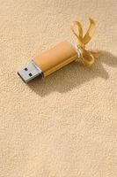 arancia USB veloce memoria carta con un' blu arco bugie su un' coperta di morbido e peloso leggero arancia vello tessuto. classico femmina regalo design per un' memoria carta foto