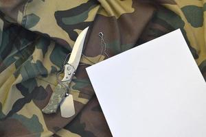 vuoto carta con coltello e esercito cane etichetta bugie su camuffare militare uniforme foto