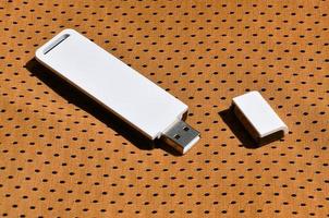 un' moderno portatile USB Wi-Fi adattatore è posto su il arancia abbigliamento sportivo fatto di poliestere nylon fibra foto