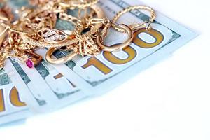 molti costoso d'oro jewerly anelli, orecchini e collane con grande quantità di noi dollaro fatture su bianca sfondo. banco dei pegni o jewerly negozio foto