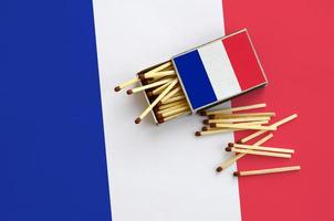 Francia bandiera è mostrato su un Aperto scatola di fiammiferi, a partire dal quale parecchi fiammiferi autunno e bugie su un' grande bandiera foto