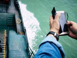 un' uomo controllo per mobile connessione su un' traghetto nel il oceano foto