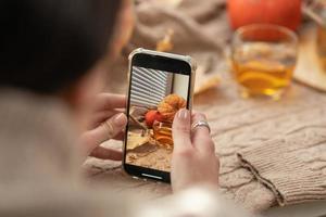 ragazza assunzione foto di zucche, autunno le foglie e teiera su un' finestra. ragazza Fotografare su Telefono rustico Halloween composizione. contento ringraziamento e Halloween