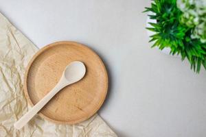 utensili in legno sul tavolo della cucina. piatto tondo, un cucchiaio, una pianta verde. il concetto di servire, cucinare, cucinare, dettagli interni. vista dall'alto foto