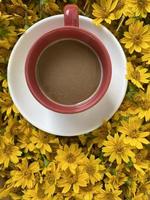 un' caffè tazza con giallo fiori su sfondo foto