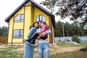 contento famiglia nel il cortile di un incompiuto Casa - Acquista di un' villetta, mutuo, prestito, trasloco, costruzione foto