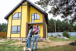 contento famiglia nel il cortile di un incompiuto Casa - Acquista di un' villetta, mutuo, prestito, trasloco, costruzione foto