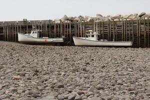 Due pesca Barche seduta su il parte inferiore a Basso marea nel il baia di finanziare foto