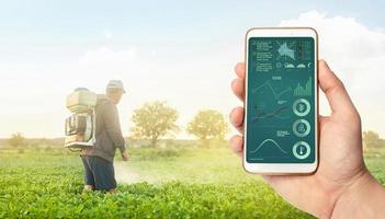 un' mano con un' Telefono su sfondo di un' contadino con agricoltura Fumo nebbia spruzzatura macchina. controllo di uso di sostanze chimiche in crescita cibo. Ritaglia pianta cura e protezione a partire dal parassiti e fungine infezione. foto