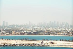 dubai centro orizzonte con spiaggia a partire dal sharjah quartiere, unito arabo Emirates o emirati arabi uniti. finanziario quartiere nel viaggio vacanza concetto. grattacieli edifici con nebbioso inquinata cielo. foto