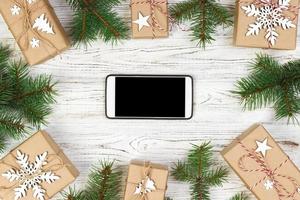 bianca nero smartphone con isolato schermo, sopra di legno scrivania con Natale decorazioni. superiore Visualizza foto