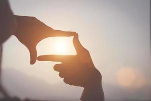 pianificazione e visione concetto di nuovo anni inizio, donna mano fabbricazione telaio gesto trova messa a fuoco a tramonto, donna guardare per prospettiva per catturare il senso di un' chiaro imminente obbiettivo. foto