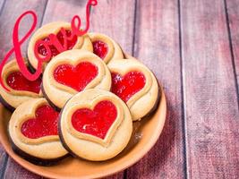 fatti in casa biscotti con un' rosso marmellata cuore San Valentino giorno buio di legno sfondo copia spazio foto