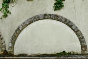 un' murato porta con un' pietra arco e contro il sfondo di un vecchio beige intonacato parete, foto telaio, testo posto