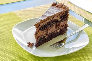 un' delicato pezzo di cioccolato torta, torte su un' bianca piatto con un' forchetta foto