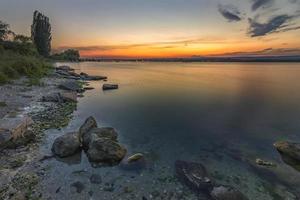 mare tramonto paesaggio marino con bagnato rocce. liscio lungo esposizione di onde foto