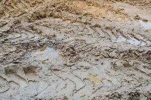 struttura di un' sporco cattivo sporco strada sporco strada con pozzanghere e argilla essiccazione fango con crepe e solchi. fuori strada. il sfondo foto