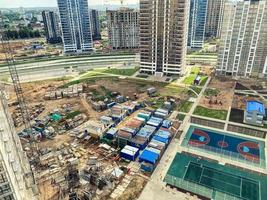 costruzione di multipiano edifici nel il città centro. confortevole campi da gioco per bambini e gli sport. sotto siamo costruzione carri, temporaneo case di persone foto