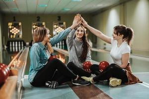tre femmina amici avendo divertimento e festeggiare nel un' bowling vicolo foto